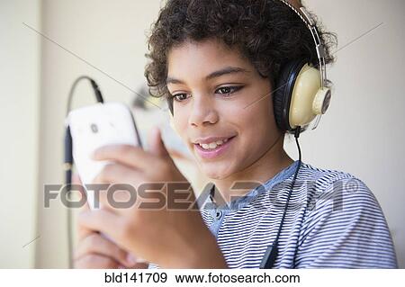 Mixed race boy listening to headphones and cell phone View Large Photo Image Stock Photo - Mixed race boy listening to headphones and cell phone. Fotosearch