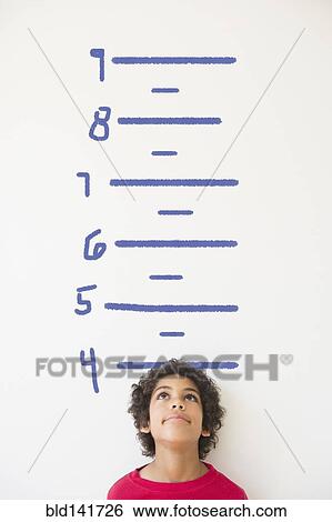 Mixed race boy measuring his height on wall chart View Large Photo Image Stock Photograph - Mixed race boy measuring his height on wall chart. Fotosearch