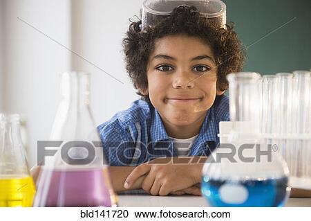 Stock Image - Mixed race boy sitting in classroom science lab. Fotosearch