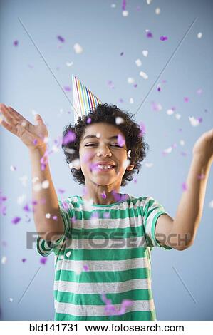 Stock Image - Mixed race boy throwing confetti at party. Fotosearch