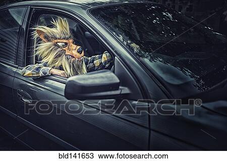 Stock Image - Mixed race boy wearing wolf mask and driving car. Fotosearch