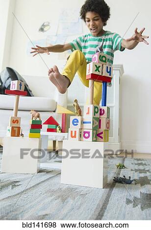 Stock Photo - Mixed race boy wrecking wooden block city in living room. Fotosearch