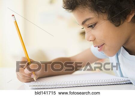 Stock Photography - Mixed race boy writing in notebook. Fotosearch