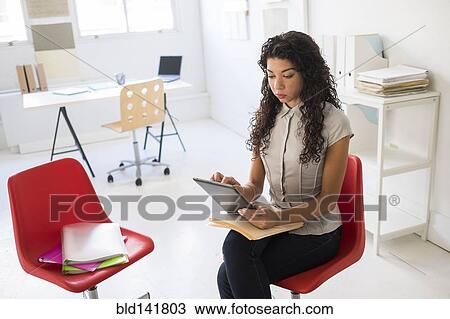Stock Image - Mixed race businesswoman using digital tablet in office. Fotosearch