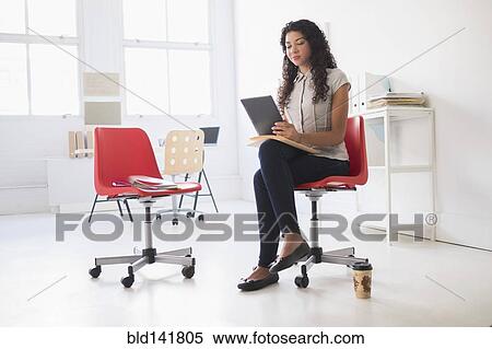 Stock Photography - Mixed race businesswoman using digital tablet in office. Fotosearch