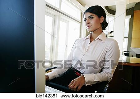 Stock Image - Mixed race businesswoman working at computer in office. Fotosearch