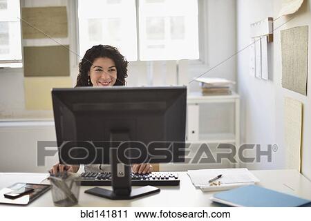 Stock Image - Mixed race businesswoman working on computer at desk in office. Fotosearch