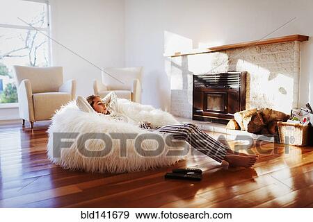 Stock Photo - Mixed race girl relaxing in beanbag chair in living room. Fotosearch