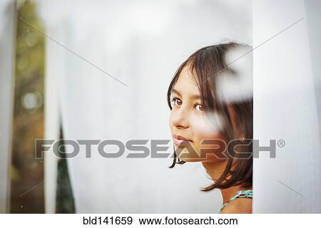 Stock Photo - Mixed race girl standing near window. Fotosearch