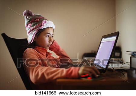 Stock Photograph - Mixed race girl using laptop at desk. Fotosearch