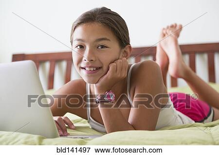 Mixed race girl using laptop on bed View Large Photo Image Stock Photo - Mixed race girl using laptop on bed. Fotosearch