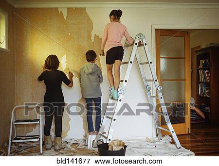 Stock Photo - Mixed race mother and children stripping wallpaper in living room. Fotosearch