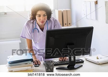 Stock Photo - Mixed race nurse using computer in office. Fotosearch