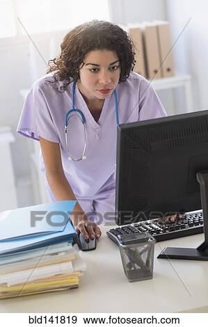 Mixed race nurse using computer in office View Large Photo Image Stock Photo - Mixed race nurse using computer in office. Fotosearch