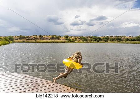 Mixed race teenage girl in inflatable ring jumping into still lake View Large Photo Image Stock Photo - Mixed race teenage girl in inflatable ring jumping into still lake. Fotosearch