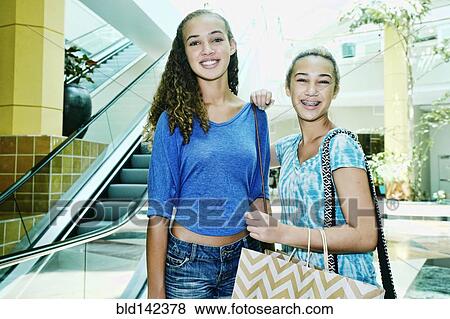 Mixed race teenage girls shopping near escalator at shopping mall View Large Photo Image Stock Photo - Mixed race teenage girls shopping near escalator at shopping mall. Fotosearch