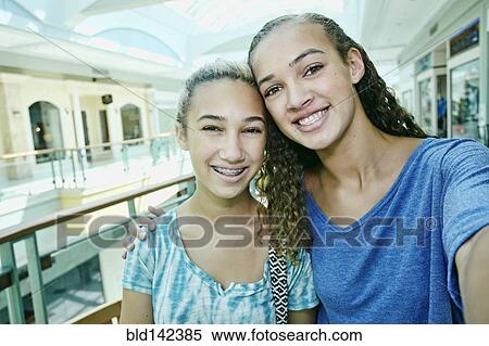 Stock Photography - Mixed race teenage girls smiling at shopping mall. Fotosearch