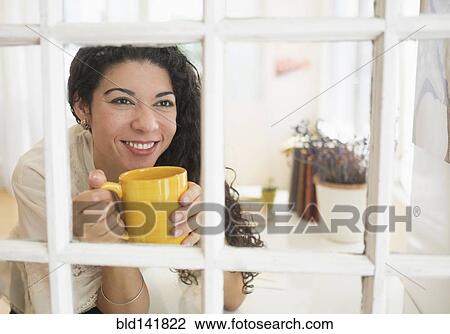 Mixed race woman drinking cup of coffee near window View Large Photo Image Stock Image - Mixed race woman drinking cup of coffee near window. Fotosearch