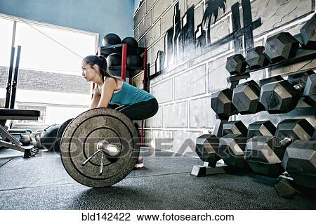 Mixed race woman lifting weights in gym View Large Photo Image Stock Image - Mixed race woman lifting weights in gym. Fotosearch