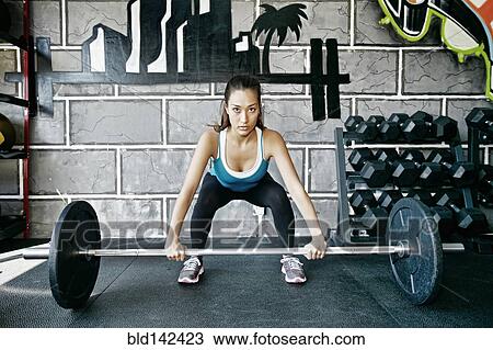 Mixed race woman lifting weights in gym View Large Photo Image Stock Image - Mixed race woman lifting weights in gym. Fotosearch