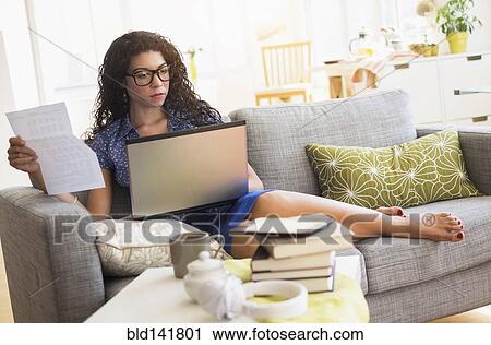 Mixed race woman paying bills on laptop on sofa View Large Photo Image Stock Image - Mixed race woman paying bills on laptop on sofa. Fotosearch