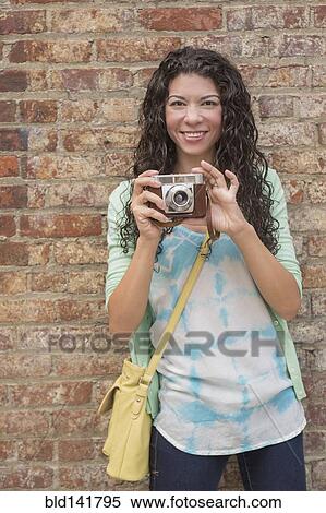 Stock Photography - Mixed race woman photographing outdoors. Fotosearch