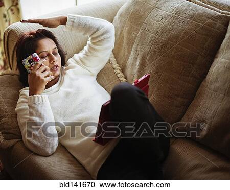 Stock Image - Mixed race woman talking on cell phone and using digital tablet. Fotosearch