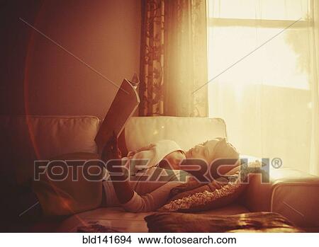 Picture - Mixed race woman using digital tablet on living room sofa. Fotosearch