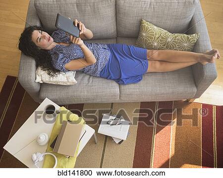Mixed race woman using digital tablet on sofa View Large Photo Image Stock Image - Mixed race woman using digital tablet on sofa. Fotosearch