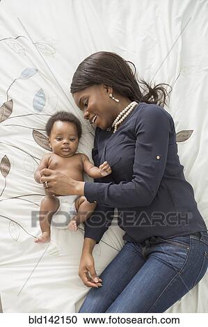 Stock Image - Mother and baby son laying on bed. Fotosearch