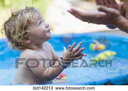 Mother and baby son playing in wading pool View Large Photo Image Stock Image - Mother and baby son playing in wading pool. Fotosearch