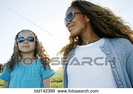 Stock Photo - Mother and daughter wearing sunglasses outdoors. Fotosearch