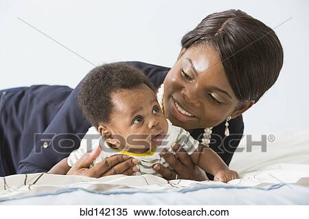 Stock Photography - Mother playing with baby son on bed. Fotosearch