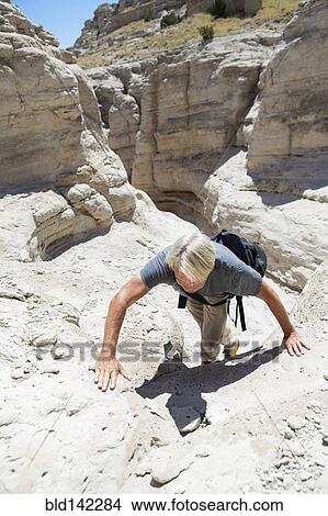 Picture - Older Caucasian man climbing rock formations. Fotosearch