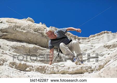 Stock Photo - Older Caucasian man climbing rock formations. Fotosearch