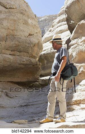 Picture - Older Caucasian man exploring rock formations. Fotosearch