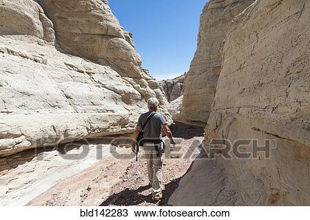 Stock Image - Older Caucasian man exploring rock formations. Fotosearch