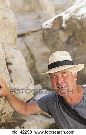 Stock Image - Older Caucasian man exploring rock formations. Fotosearch