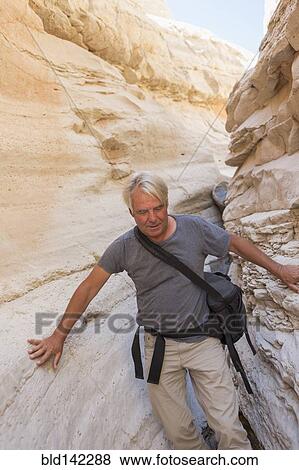 Stock Photo - Older Caucasian man exploring rock formations. Fotosearch