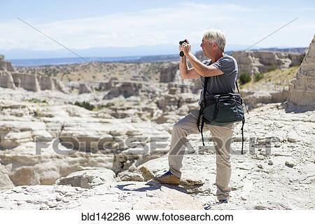 Stock Photograph - Older Caucasian man photographing rock formations, Abiquiu, New Mexico, United States. Fotosearch