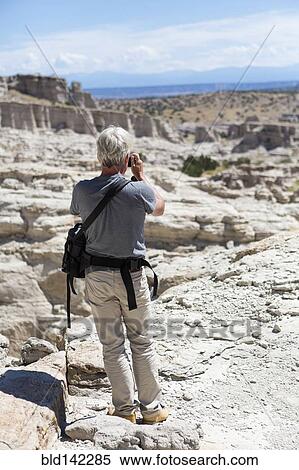 Stock Photography - Older Caucasian man photographing rock formations, Abiquiu, New Mexico, United States. Fotosearch