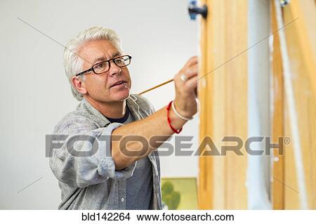 Picture - Older Hispanic artist painting in studio. Fotosearch