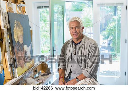 Stock Photograph - Older Hispanic artist smiling in studio. Fotosearch