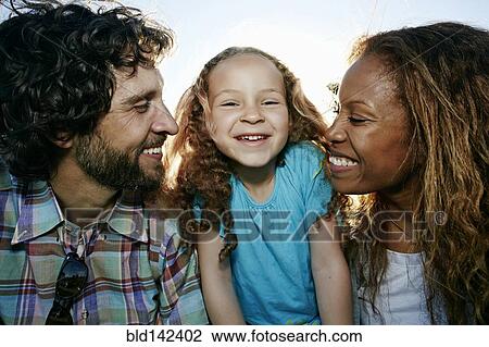Stock Image - Parents and daughter smiling together outdoors. Fotosearch