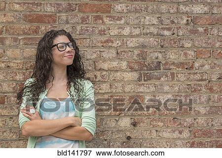 Stock Photo - Pensive mixed race woman standing with arms crossed. Fotosearch