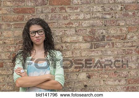 Stock Photograph - Pensive mixed race woman standing with arms crossed. Fotosearch