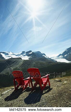 Stock Photography - Red lawn chairs overlooking scenic mountain landscape. Fotosearch