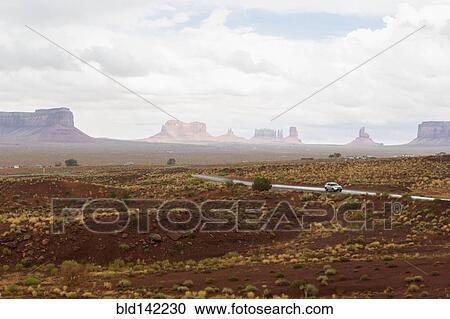 Stock Image - Rock formations and remote road in desert landscape. Fotosearch
