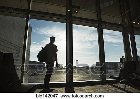 Silhouette of man looking out airport window View Large Photo Image Stock Photo - Silhouette of man looking out airport window. Fotosearch