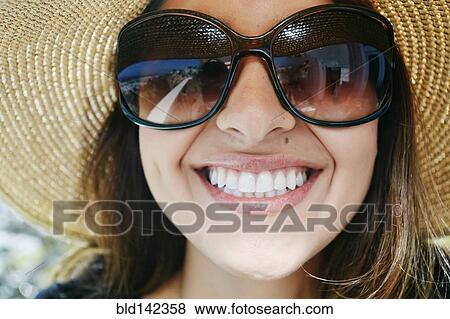 Stock Photo - Smiling mixed race woman wearing sunglasses and sun hat. Fotosearch